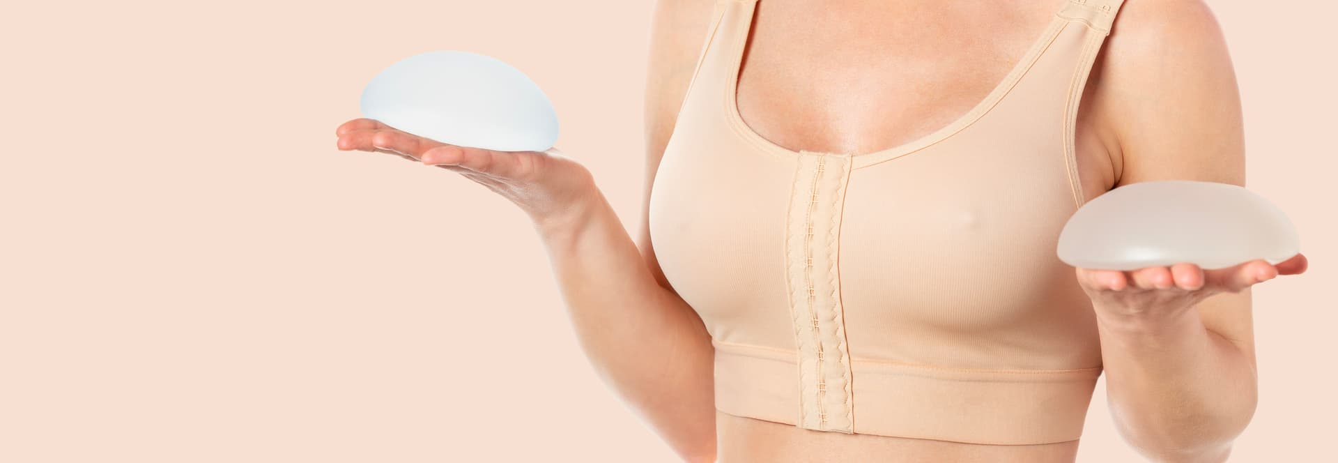 Mulher usando sutiã cirúrgico e segurando próteses de silicone